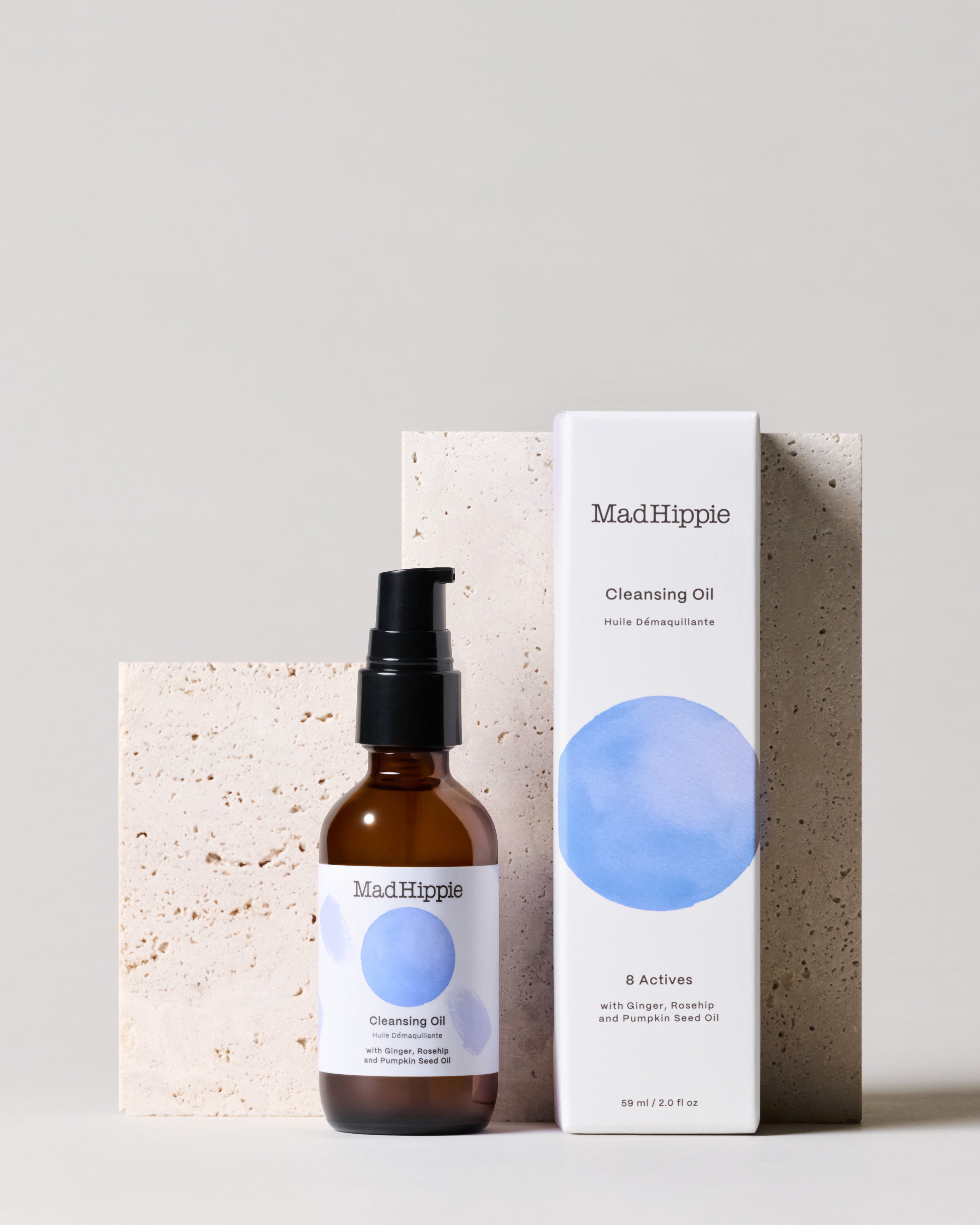 Cleansing Oil bottle + box in front of stone slab, with gray background
