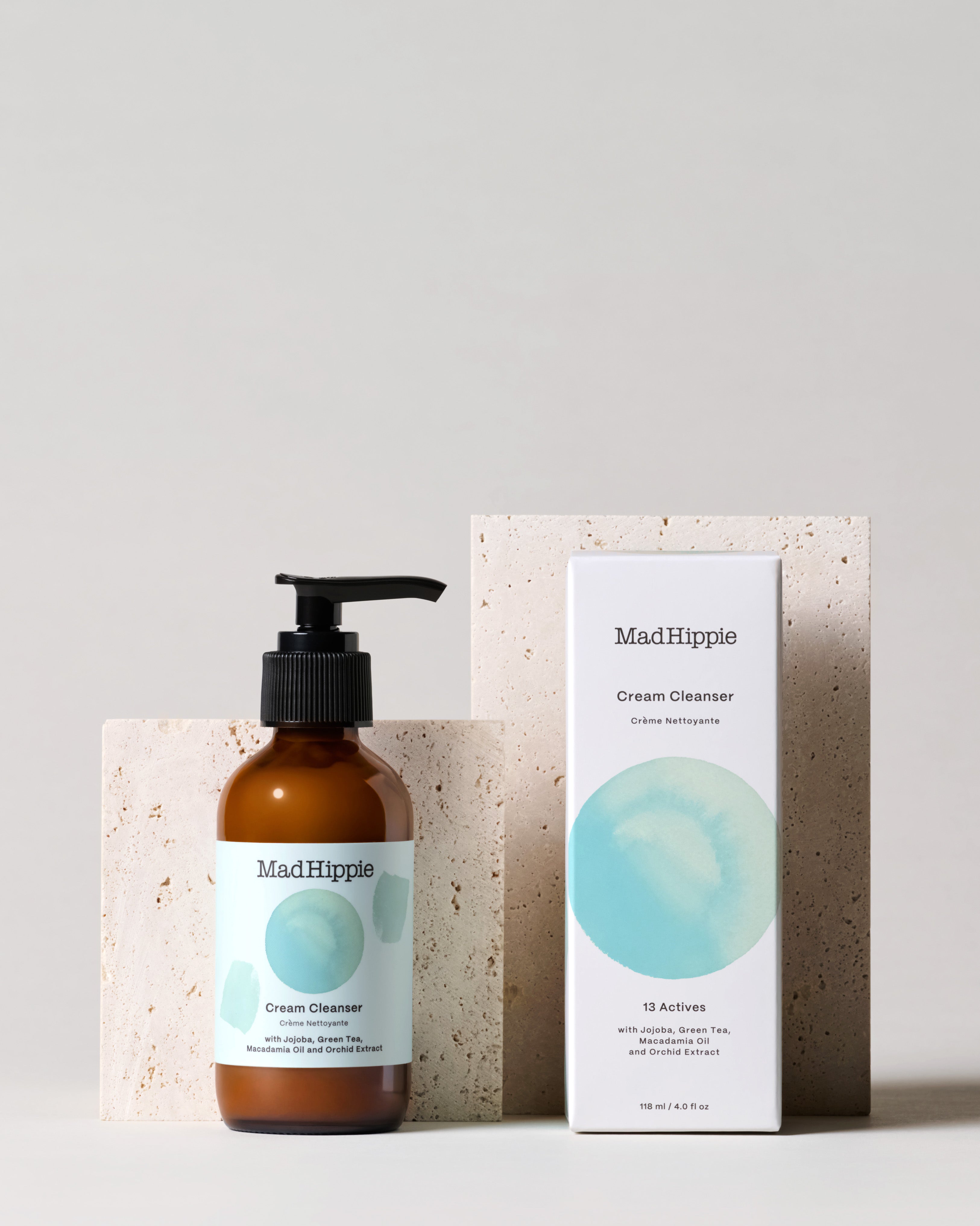Cream Cleanser bottle + box in front of stone slabs, with gray background