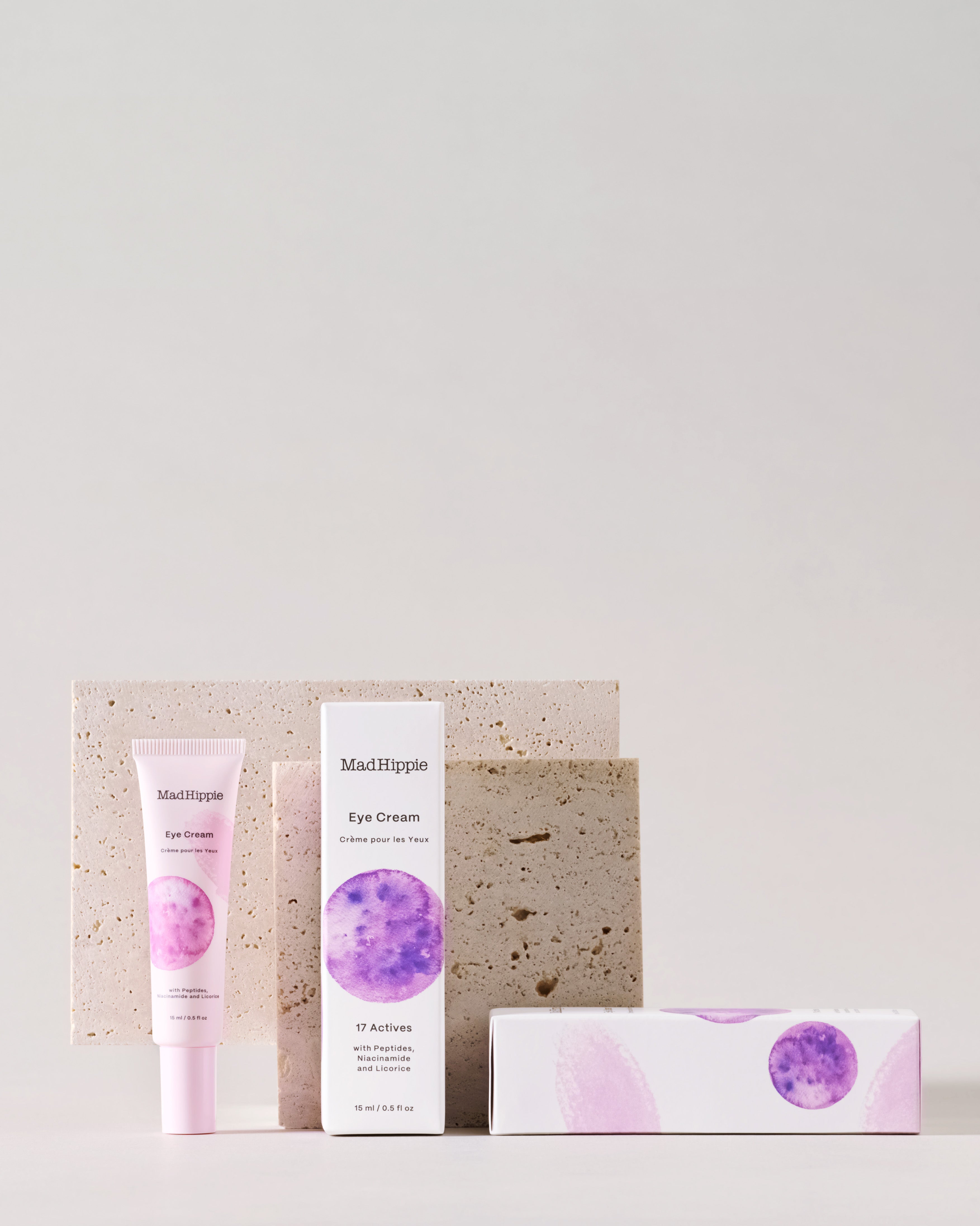 Eye Cream tube + boxes in front of stone slabs, with gray background