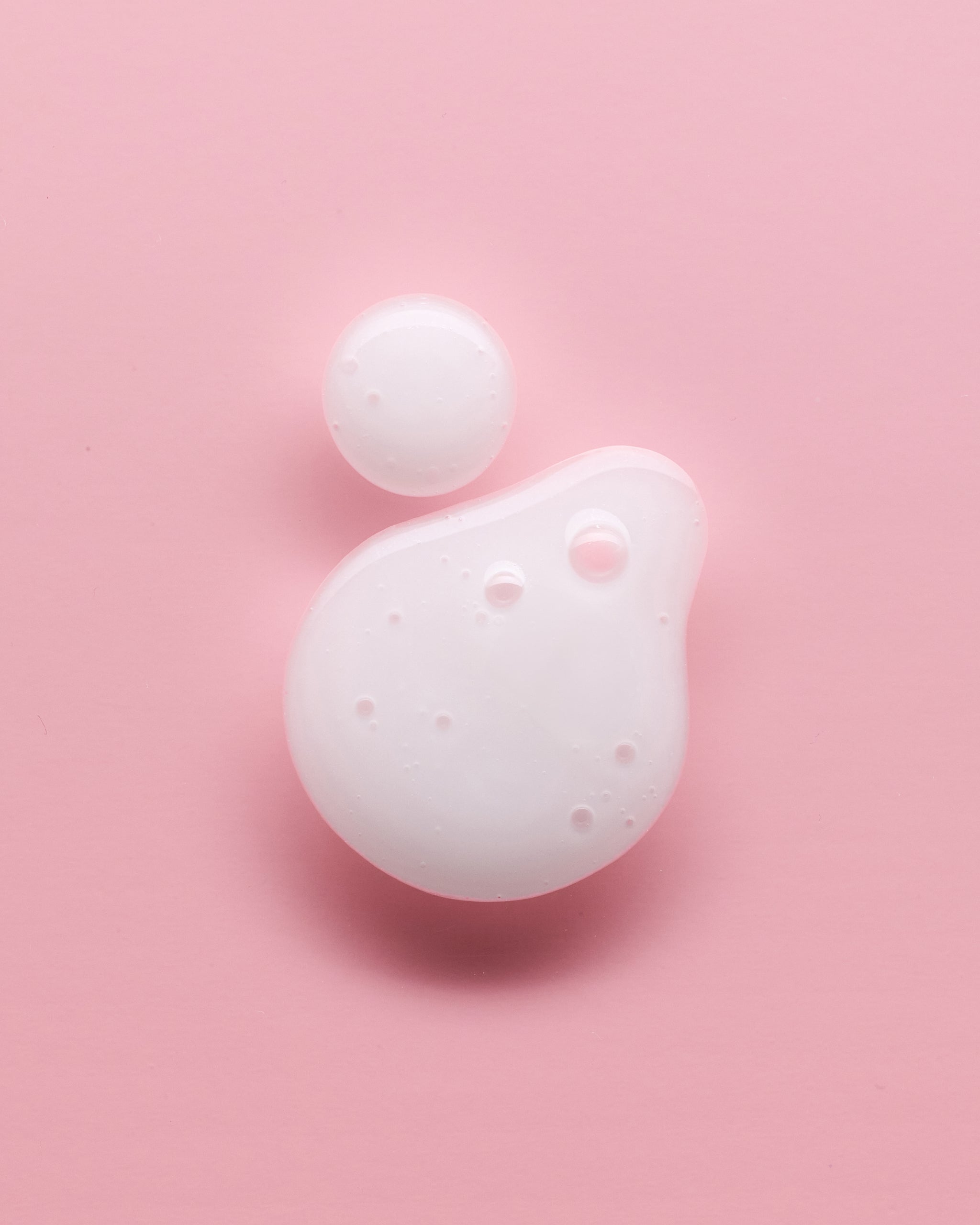 Drops of Corrective Peptide Serum on pink background