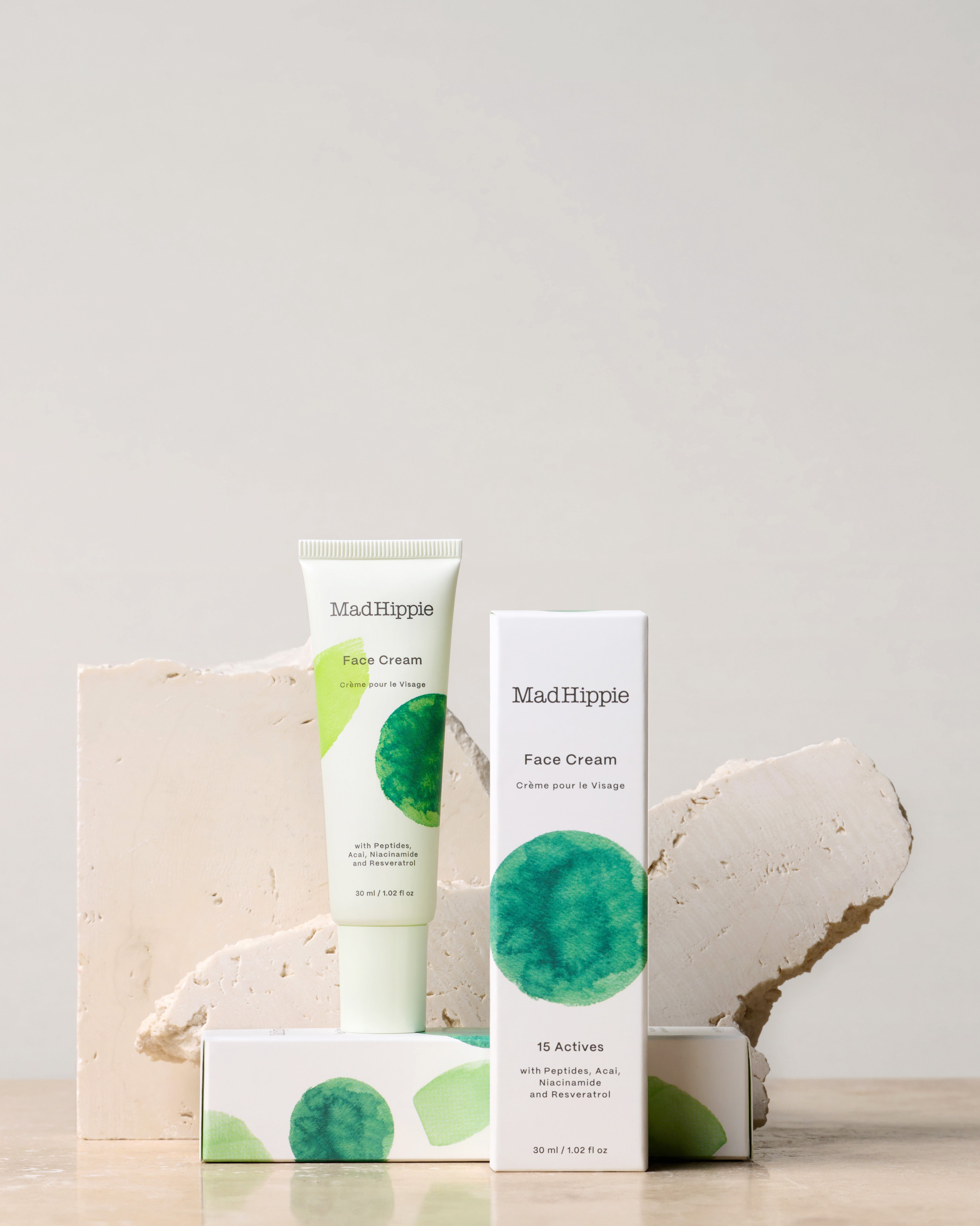 Face Cream tube + two boxes in front of stone slabs, with gray background