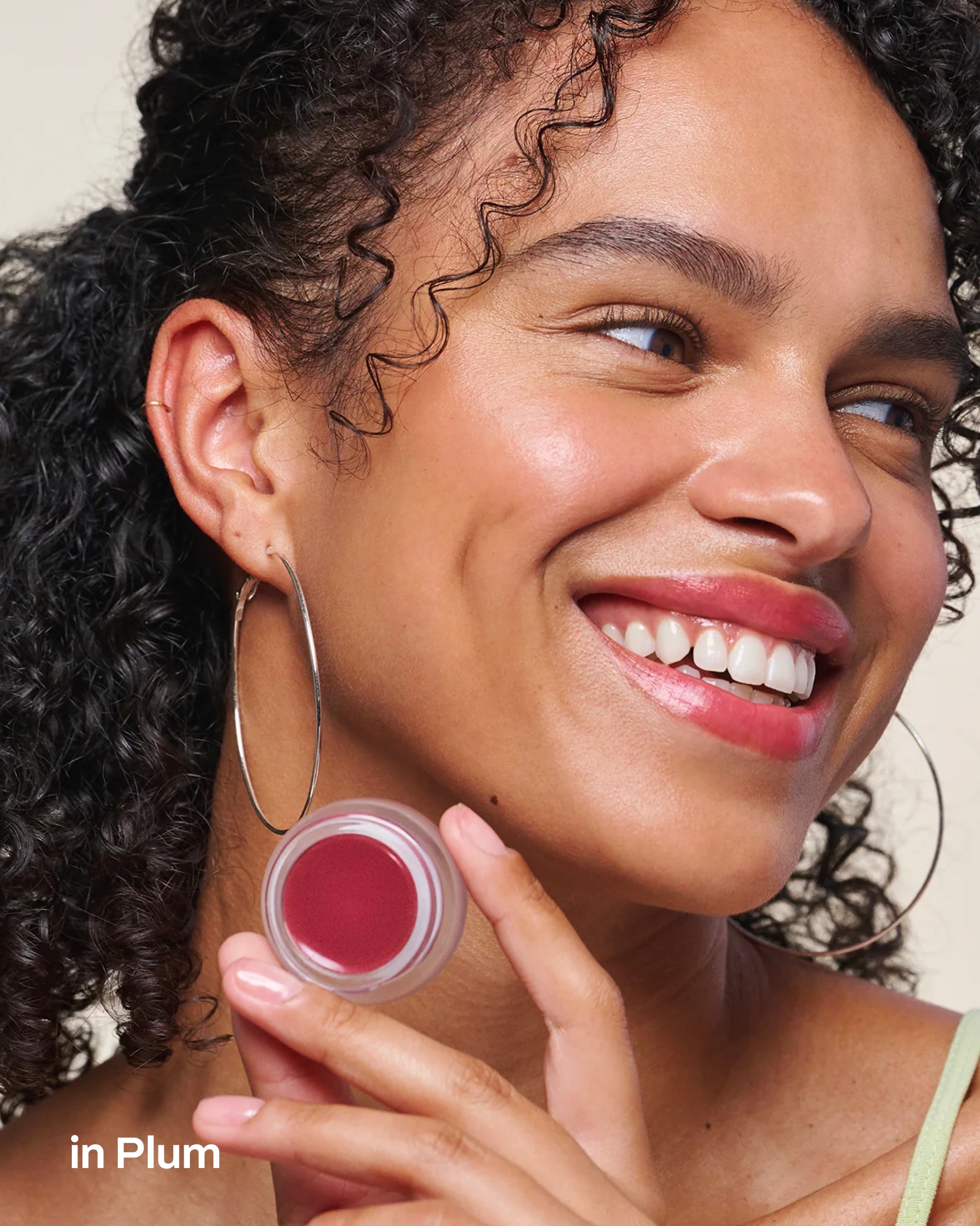 Model wearing and holding an open Plum Cheek & Lip Tint