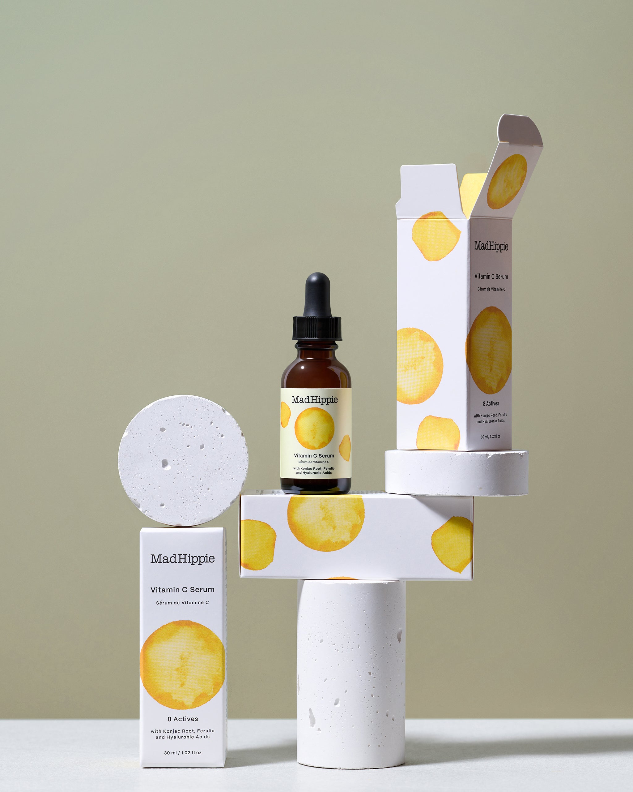 Vitamin C Serum bottle + boxes, sitting on stone slabs, with pale green background