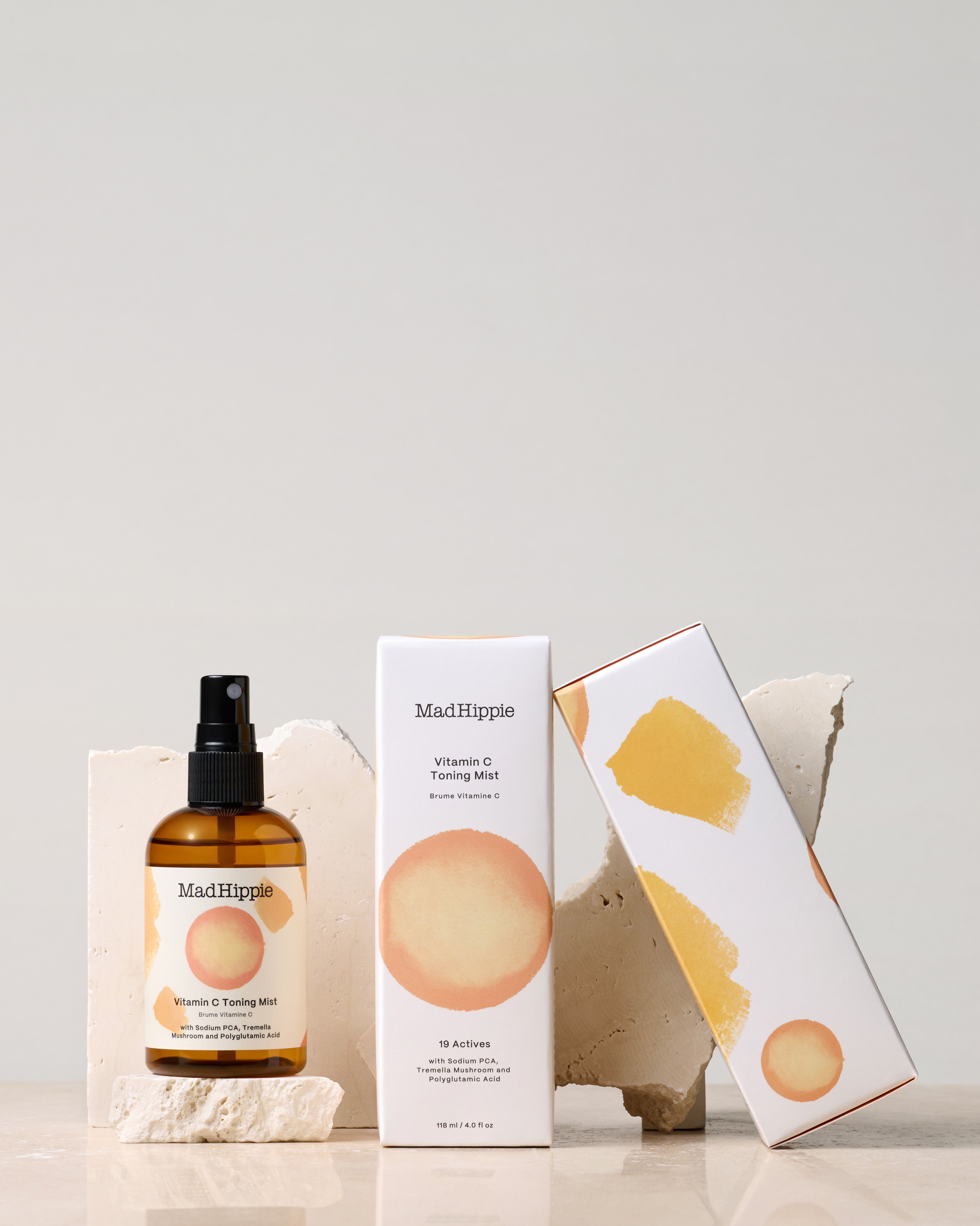 Vitamin C Toning Mist + two boxes in front of stone slabs, with gray background